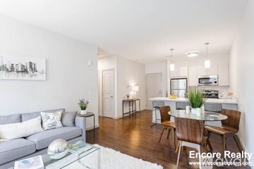 Brookline apartment for rent - A living room with a grey couch, a glass coffee table, and a dining table with chairs.