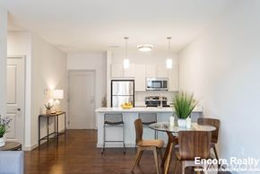 Brookline apartment for rent - A dining room with a table set for two and a kitchen area in the background.