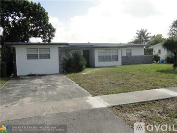 Oakland Park house for rent - A white house with a grey roof and a concrete driveway.