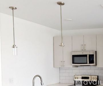 Boston apartment for rent - A kitchen with white cabinets and a microwave.