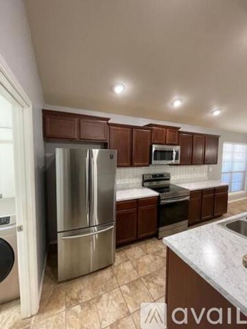 Lubbock house for rent - A kitchen with brown cabinets and a stainless steel refrigerator.