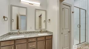 Lewisville apartment for rent - A bathroom with a granite countertop and a glass shower door.