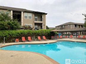 New Braunfels apartment for rent - A swimming pool surrounded by red chairs and apartment buildings.