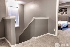 Irving apartment for rent - A bedroom with a bed, a window with blinds, and a staircase.
