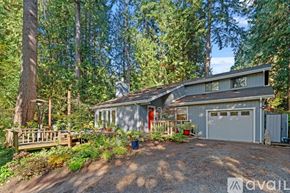 Bainbridge Island apartment for rent - A house with a garage is surrounded by trees and has a gravel driveway.