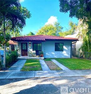 Miami apartment for rent - A white house with a red tile roof is surrounded by greenery.