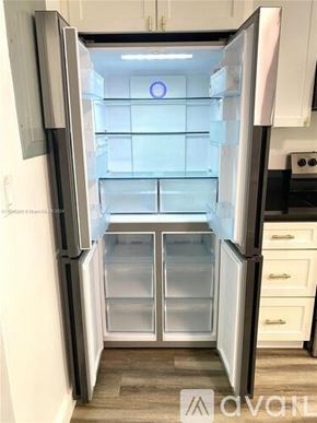 Miami apartment for rent - A white refrigerator with its door open and empty.