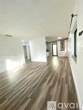 Miami apartment for rent - A long hallway with wood floors and white walls.