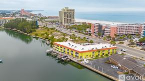 St. Pete Beach apartment for rent - A yellow building sits on a dock by a body of water.