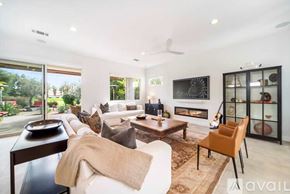 La Quinta house for rent - A modern living room with a fireplace and a glass door cabinet.