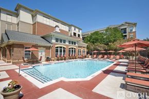 Tysons apartment for rent - A large outdoor swimming pool surrounded by lounge chairs and umbrellas.