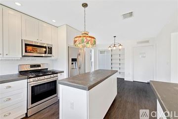 Miami house for rent - A modern kitchen with white cabinets and a wooden island.