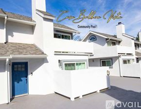 Los Angeles condo for rent - A white building with a blue door and the words "Cove Ballina View Community Pool!" written on the top.