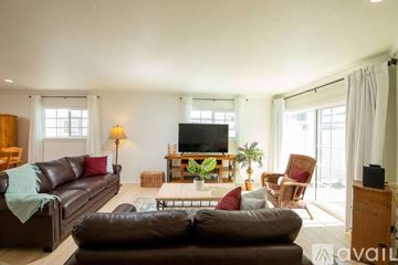 Los Angeles condo for rent - A living room with a brown leather couch and a wooden cabinet.