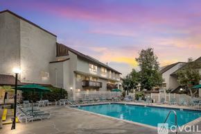 San Diego condo for rent - A pool area with chairs and umbrellas in front of a building.