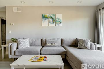 San Diego condo for rent - A living room with a grey couch and a painting on the wall.
