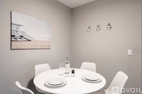 San Diego condo for rent - A dining room with a white table set for two and a picture of a beach house on the wall.