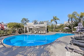 San Diego condo for rent - A large outdoor swimming pool surrounded by lounge chairs and umbrellas.