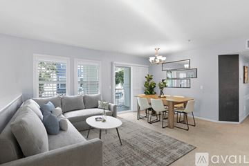 San Diego condo for rent - A living room with a grey couch, a white coffee table, and a dining table with chairs.