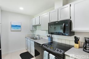 San Diego condo for rent - A kitchen with white cabinets and a black microwave.