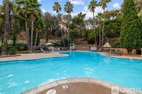 San Diego condo for rent - A large swimming pool surrounded by palm trees and a mountain in the background.