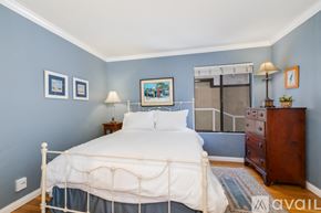 San Diego condo for rent - A bedroom with a white bed and a wooden dresser.