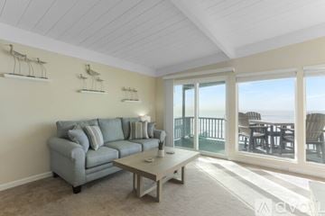 Imperial Beach condo for rent - A living room with a grey couch and a glass door leading to a balcony.