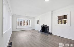 Detroit house for rent - A spacious living room with a fireplace and a view of the city through the windows.