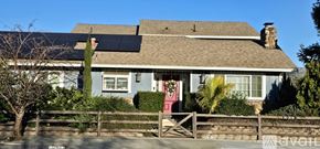 San Jose apartment for rent - A house with solar panels on the roof and a fence in front.