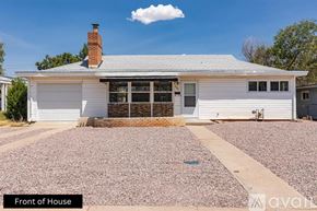 Pueblo house for rent - A white house with a grey roof and a chimney is shown from the front.