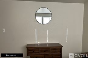 Pueblo house for rent - A round mirror hangs on a wall above a wooden dresser in Bedroom 1.