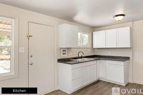 Pueblo house for rent - A kitchen with white cabinets and a black countertop.