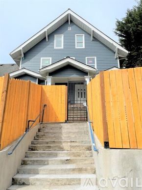 Seattle apartment for rent - A blue house with a wooden fence and stairs leading to the front door.