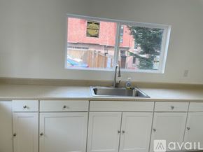 Seattle apartment for rent - A kitchen with white cabinets and a window overlooking a backyard.