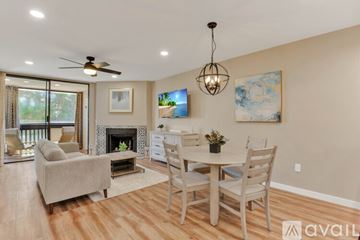 San Diego condo for rent - A living room with a fireplace, a couch, a chair, a dining table and a painting on the wall.