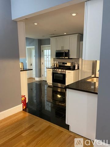 Boston apartment for rent - A kitchen with white cabinets and black countertops.