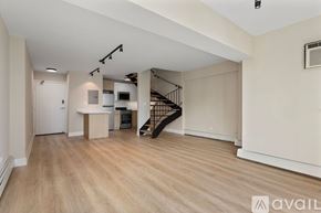 Chicago apartment for rent - A spacious room with wooden flooring and a staircase with a metal railing.