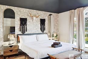 Desoto house for rent - A bedroom with a stone wall and a bed with white bedding.