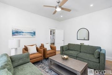 Charlottesville apartment for rent - A living room with a green couch, a brown chair, and a painting of a mountain scene on the wall.