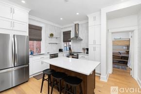 Charlottesville apartment for rent - A kitchen with white cabinets and a large island with black stools.