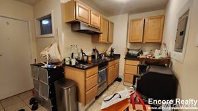 Boston apartment for rent - A kitchen with wooden cabinets and a black countertop.