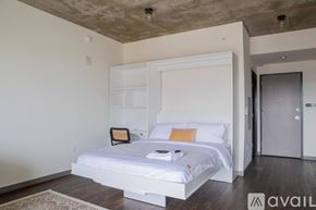 Milwaukee apartment for rent - A bedroom with a white bed and a wooden floor.