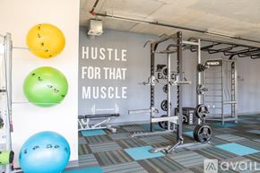 Milwaukee apartment for rent - A gym with a sign that says "Hustle for that muscle" and exercise equipment.