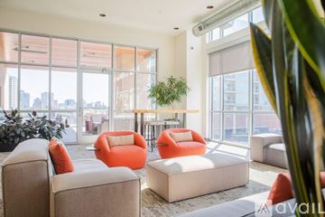 Milwaukee apartment for rent - A living room with orange chairs and a large window overlooking a cityscape.