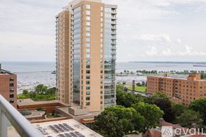 Milwaukee apartment for rent - A tall building with many windows stands in front of a body of water.