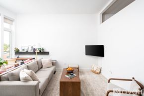 Milwaukee apartment for rent - A living room with a grey couch, a wooden coffee table, and a flat screen TV mounted on the wall.
