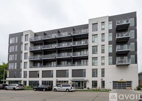 Milwaukee apartment for rent - A large apartment building with multiple balconies and cars parked in front.