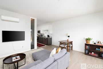 Milwaukee apartment for rent - A living room with a grey couch and a television on the wall.