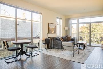 Milwaukee apartment for rent - A living room with a table and chairs in front of a large window.