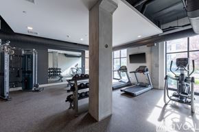 Milwaukee apartment for rent - A spacious gym with a variety of equipment including a treadmill, weights, and a television.